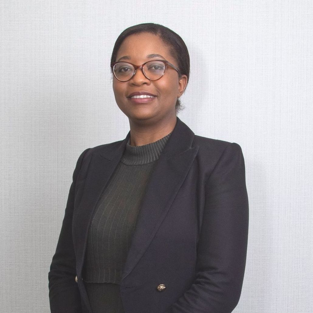 A woman wearing glasses and a black jacket smiles for the camera