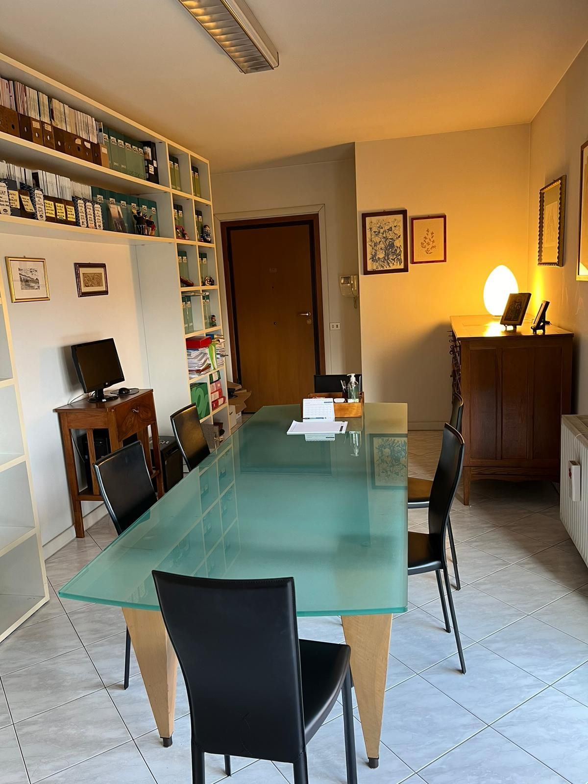 Sala conferenze con un grande tavolo con piano verde, sedie nere e scaffali portadocumenti.