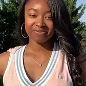 A woman wearing a pink tank top and hoop earrings is smiling for the camera.
