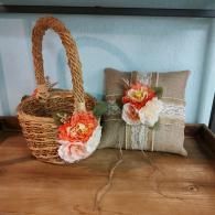A woven flower girl basket and matching burlap ring bearer pillow, both decorated with white lace and peach flowers.