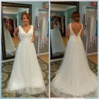 A person in a white wedding gown with a V-neck and open back, shown from the front and back in a boutique dressing room.