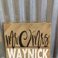 A wooden plaque with black cursive text 
