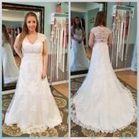 Front and back views of a bride in a white A-line lace wedding dress with a V-neckline and train in a bridal shop.