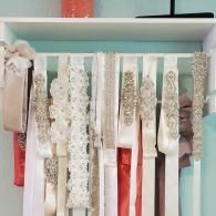 A rack displaying various wedding bridal sashes and belts adorned with beads, pearls, and rhinestones.