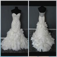 Front and back view of a white, strapless, beaded mermaid-style wedding dress with a ruffled skirt on a mannequin.