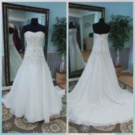 Front and back view of a white, strapless, A-line wedding dress with lace embroidery on a mannequin in a store.