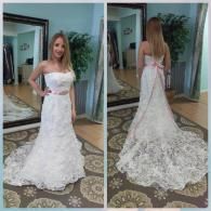 A split view of a person wearing a strapless, floral-patterned white wedding dress with a pink sash in a bridal boutique.