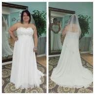 A person wearing a white, strapless, floor-length wedding dress with a veil, shown from the front and back in a mirror.