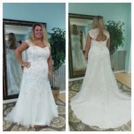 A woman tries on a floor-length white lace wedding dress shown from the front and back in a mirror at a boutique.