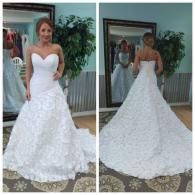 A person wearing a white, sweetheart-neckline wedding dress with a full, textured floral skirt, shown front and back.