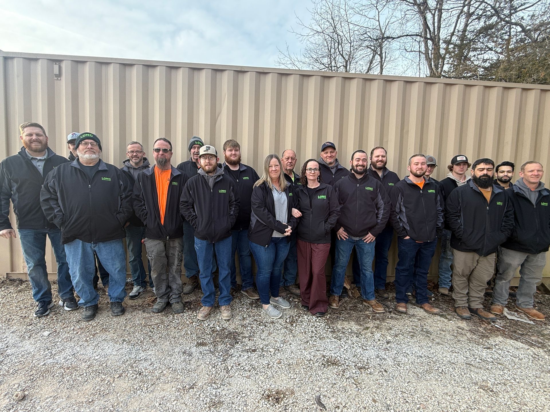Technician in red shirt working on a white heat pump outside a brick building.