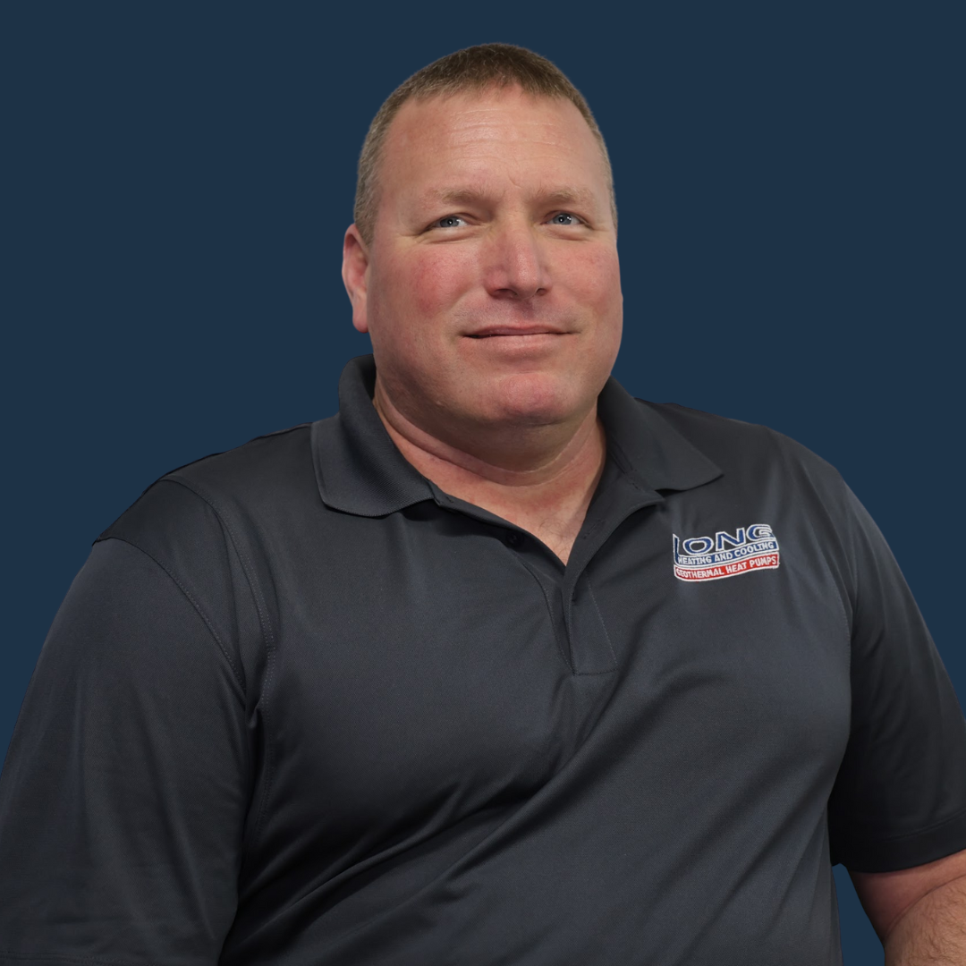 Man in black polo shirt smiling, standing against a blue backdrop.
