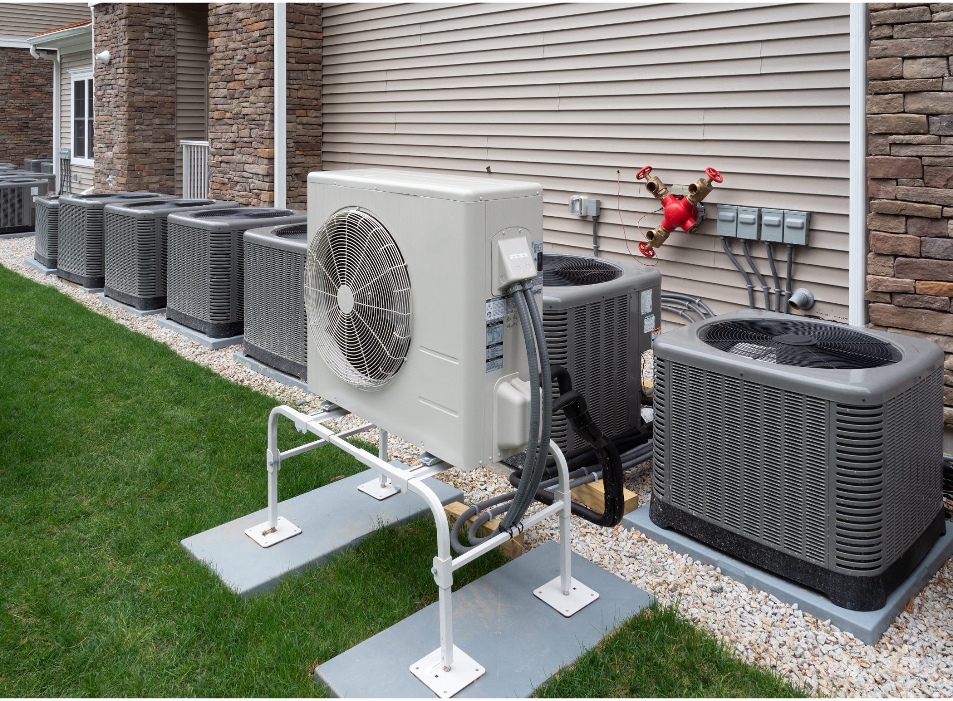 Air conditioning units lined up on green grass next to a building.