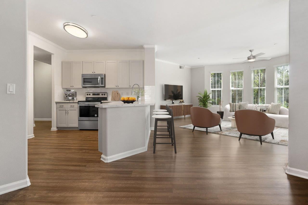 Open-concept kitchen with island and living area in a modern apartment.