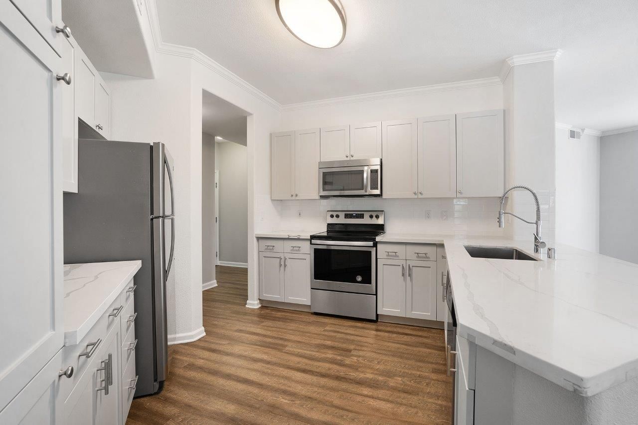Modern kitchen with white cabinets, stainless steel refrigerator and stove, and a large island.