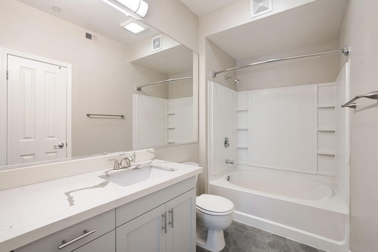 Bathroom in an apartment with a white vanity, toilet, and bathtub/shower.