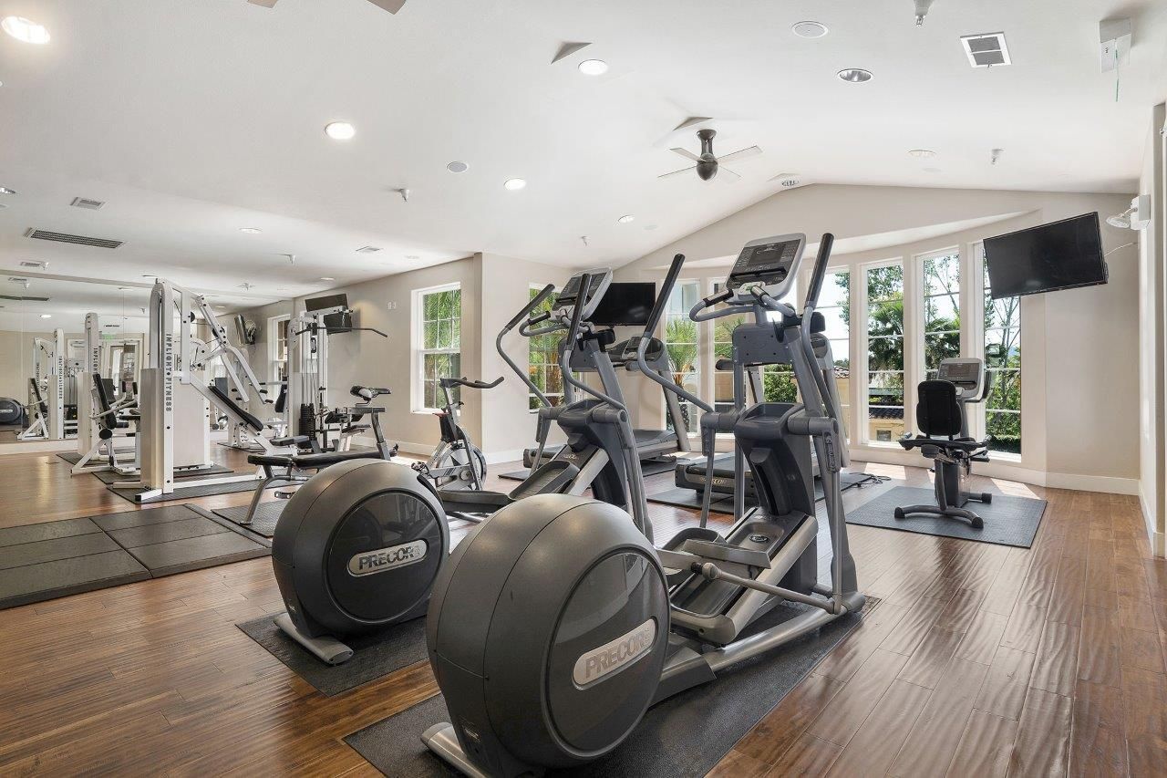 Bright gym with treadmills, ellipticals, and weight machines in a spacious community fitness center.