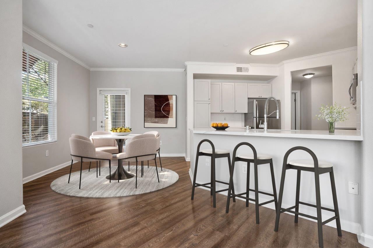Open-concept kitchen and dining area in a modern apartment with a kitchen island and bar stools.
