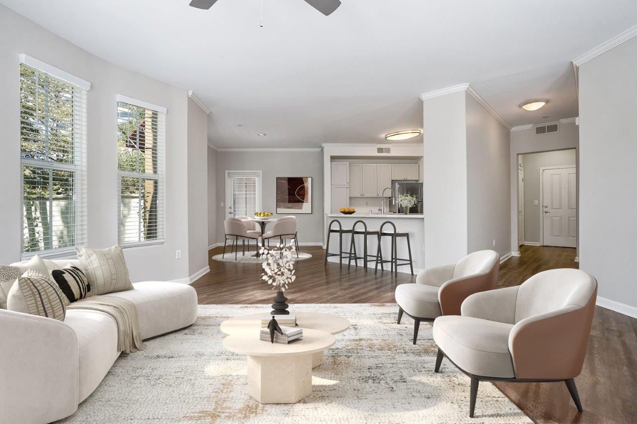 Open-concept living area with a beige sofa, accent chairs, and a kitchen island in the background.