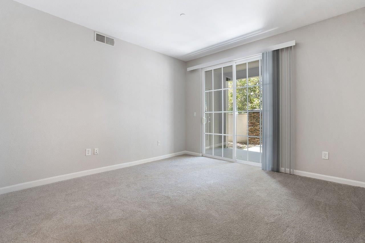 Living room with sliding glass door to patio, neutral walls, and carpet.