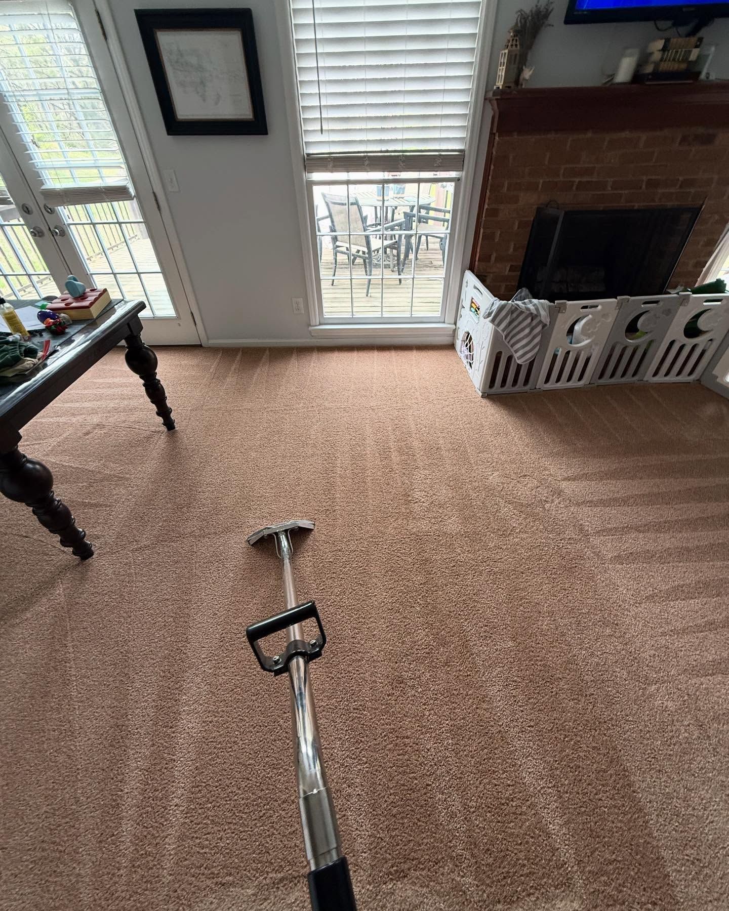 A vacuum cleaner is cleaning a carpet in a living room.