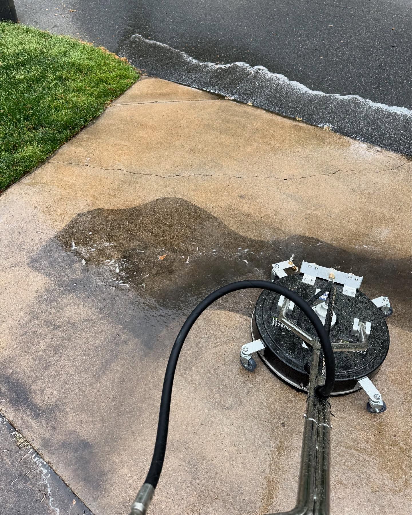 A pressure washer is being used to clean a concrete driveway.