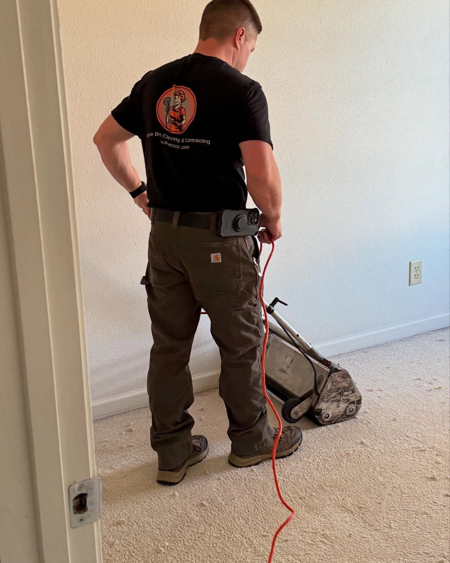 A man is cleaning a carpet with a machine in a room.