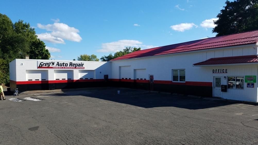 Exterior of Guy's Auto Repair building; white walls with red and black trim, red roof, blue sky | Greg's Auto Repair