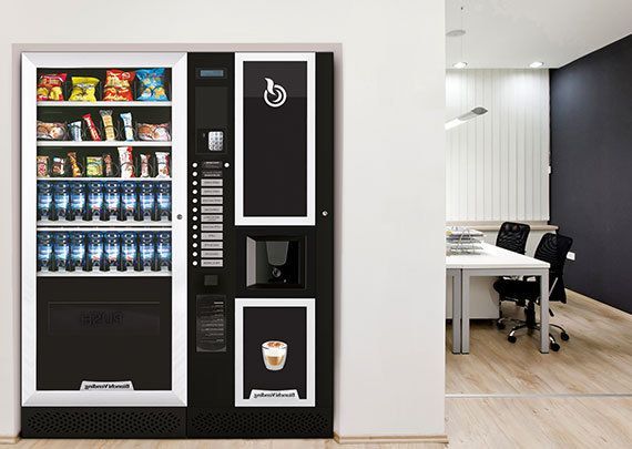 Distributore automatico di snack e caffè contro una parete bianca in un ufficio.