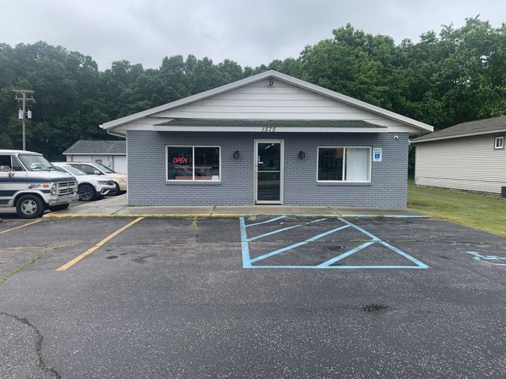 A small building with a parking lot in front of it.