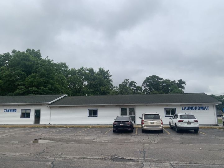A white building with cars parked in front of it on a cloudy day.