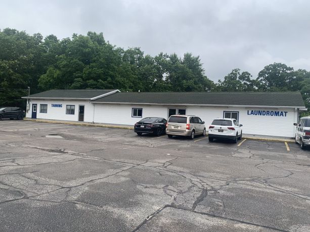 A row of cars are parked in front of a laundromat.