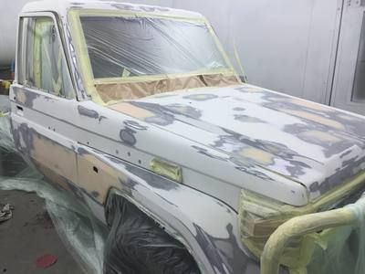 a white truck is being painted in a garage .