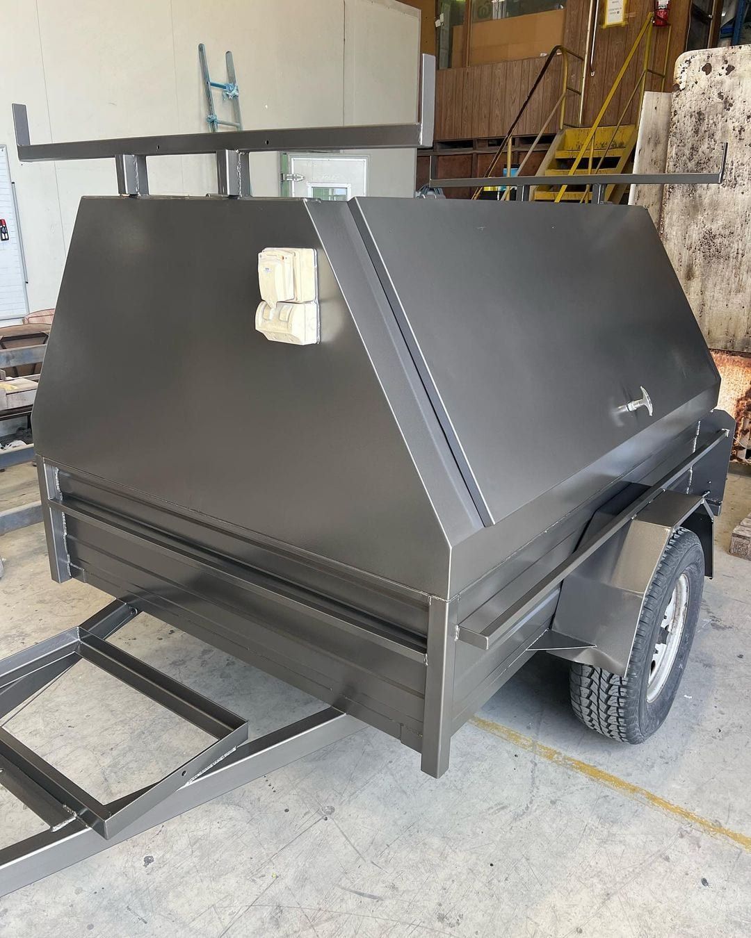 a black trailer with a canopy on top of it is parked in a garage .