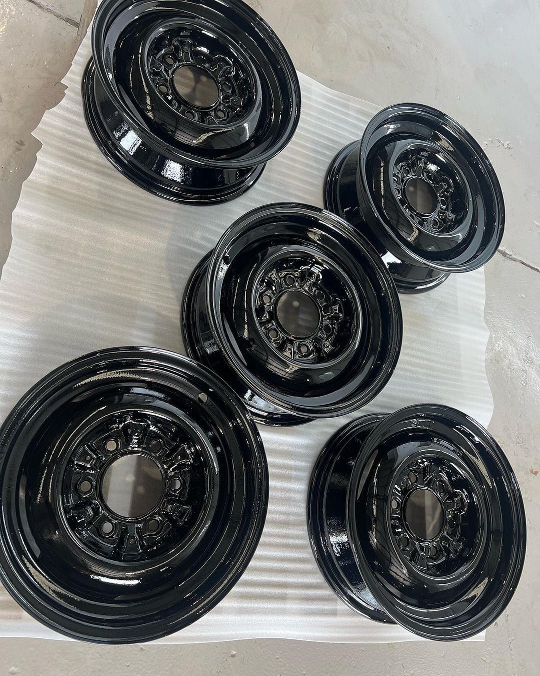 a group of black wheels are sitting on top of each other on a white surface .