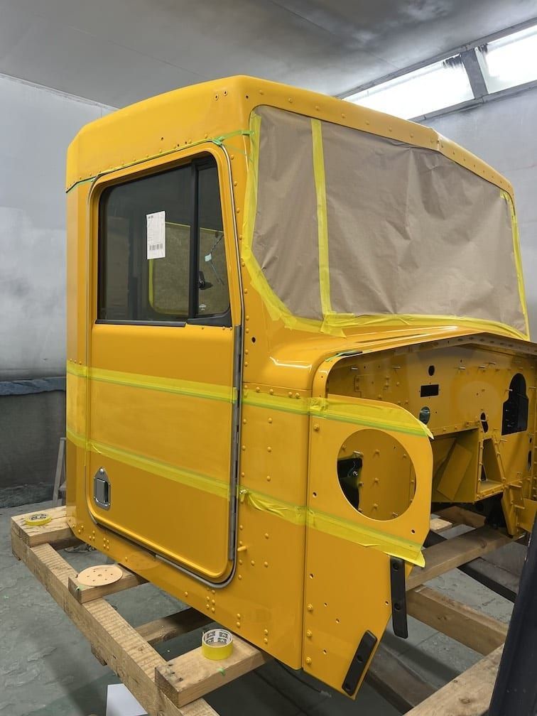 A yellow truck cab is sitting on top of a wooden pallet.