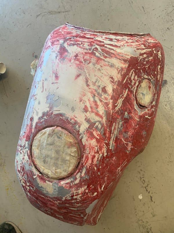 a red and white object is sitting on a table getting ready for sand blasting