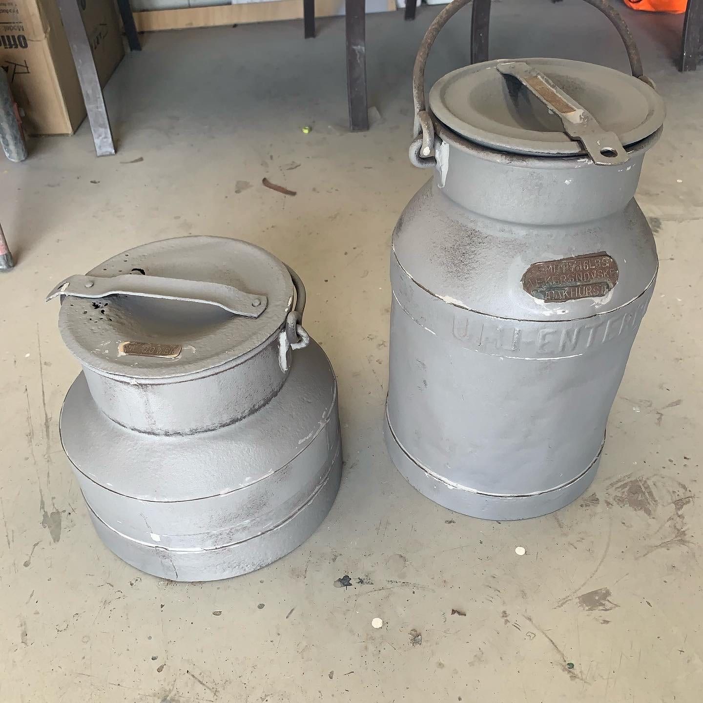 Two milk cans are sitting next to each other on the floor