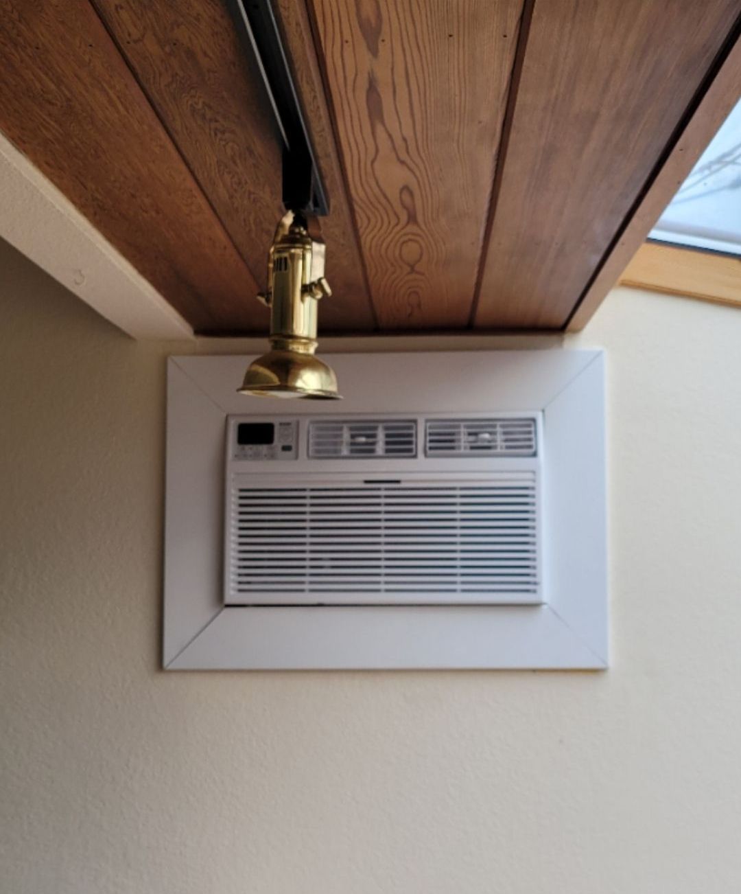 A ceiling mounted air conditioner with a light hanging from it