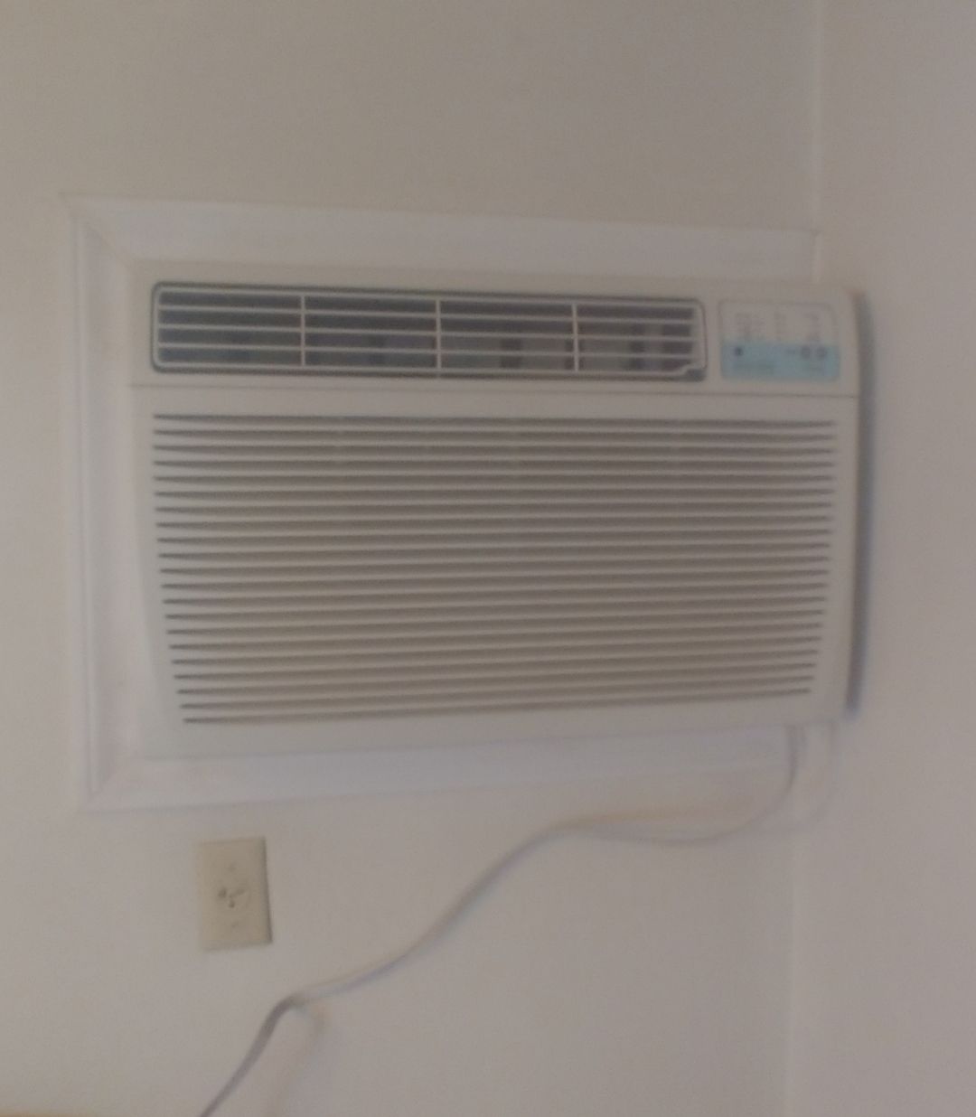 A white air conditioner is hanging on a white wall