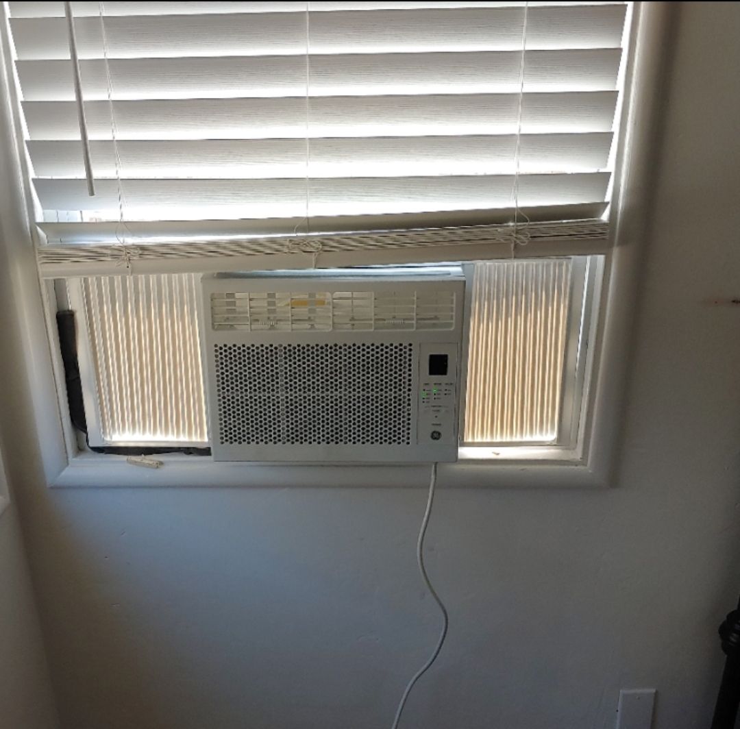 A window with blinds and an air conditioner in it