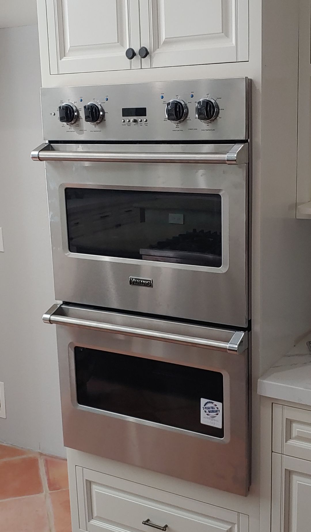 A stainless steel oven is sitting on top of a white cabinet in a kitchen.