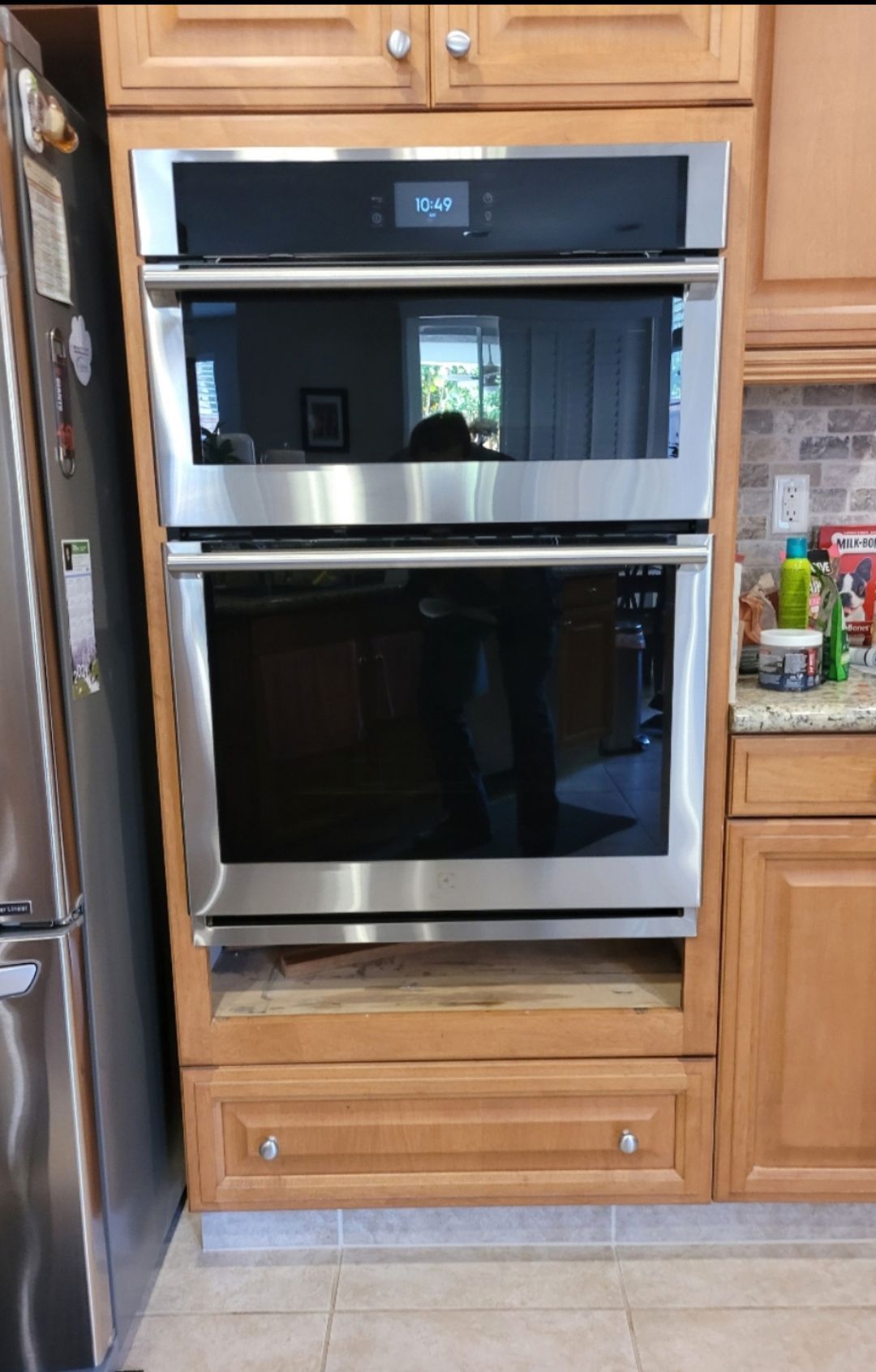 A stainless steel oven is sitting in a kitchen next to a refrigerator.