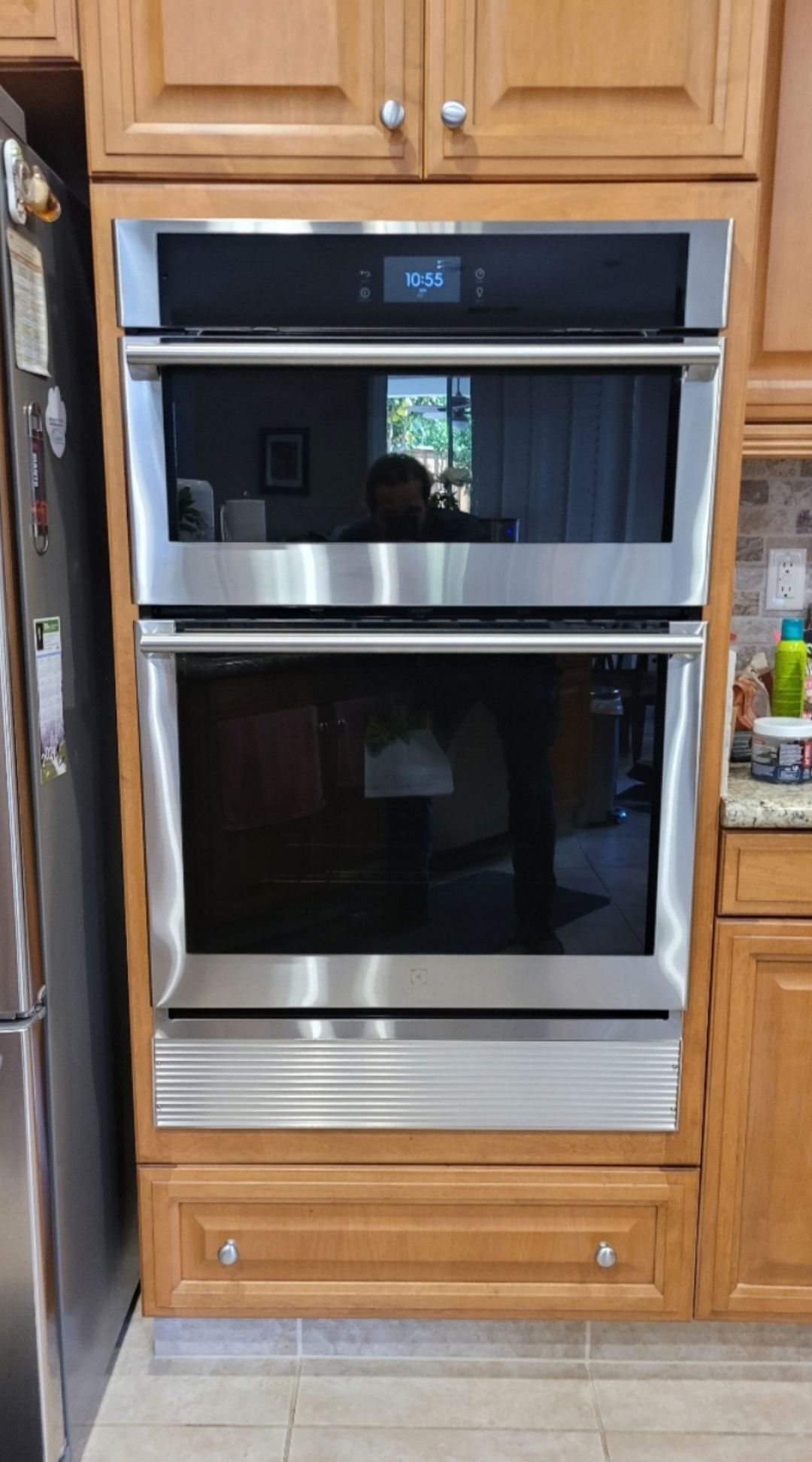 A stainless steel double oven is sitting on top of a wooden cabinet in a kitchen.