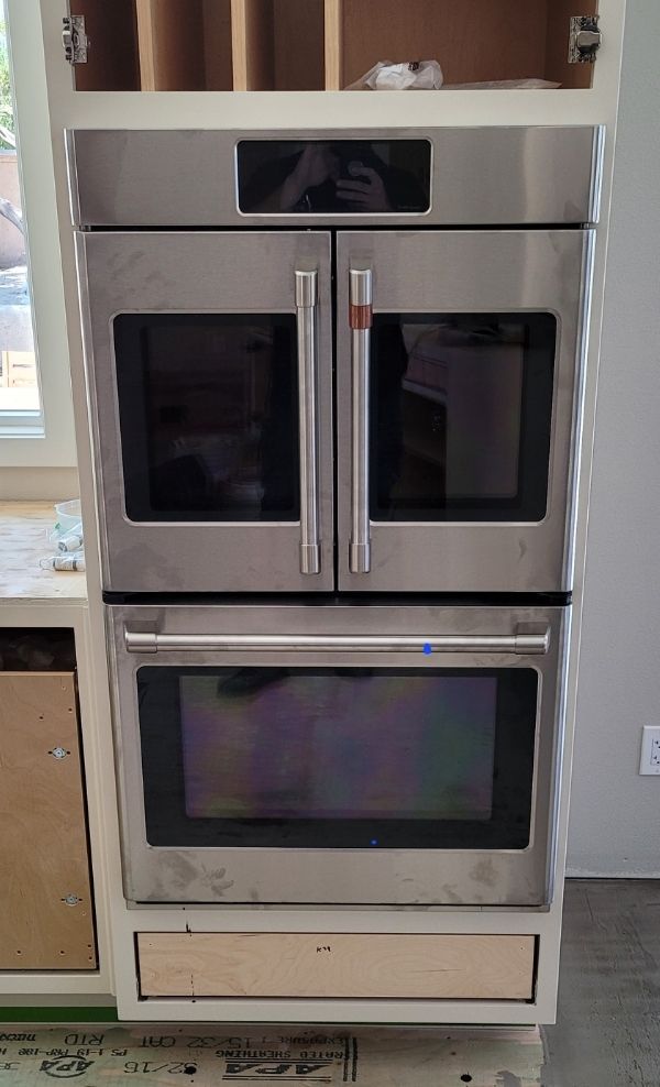 A stainless steel oven is sitting on top of a cabinet in a kitchen.
