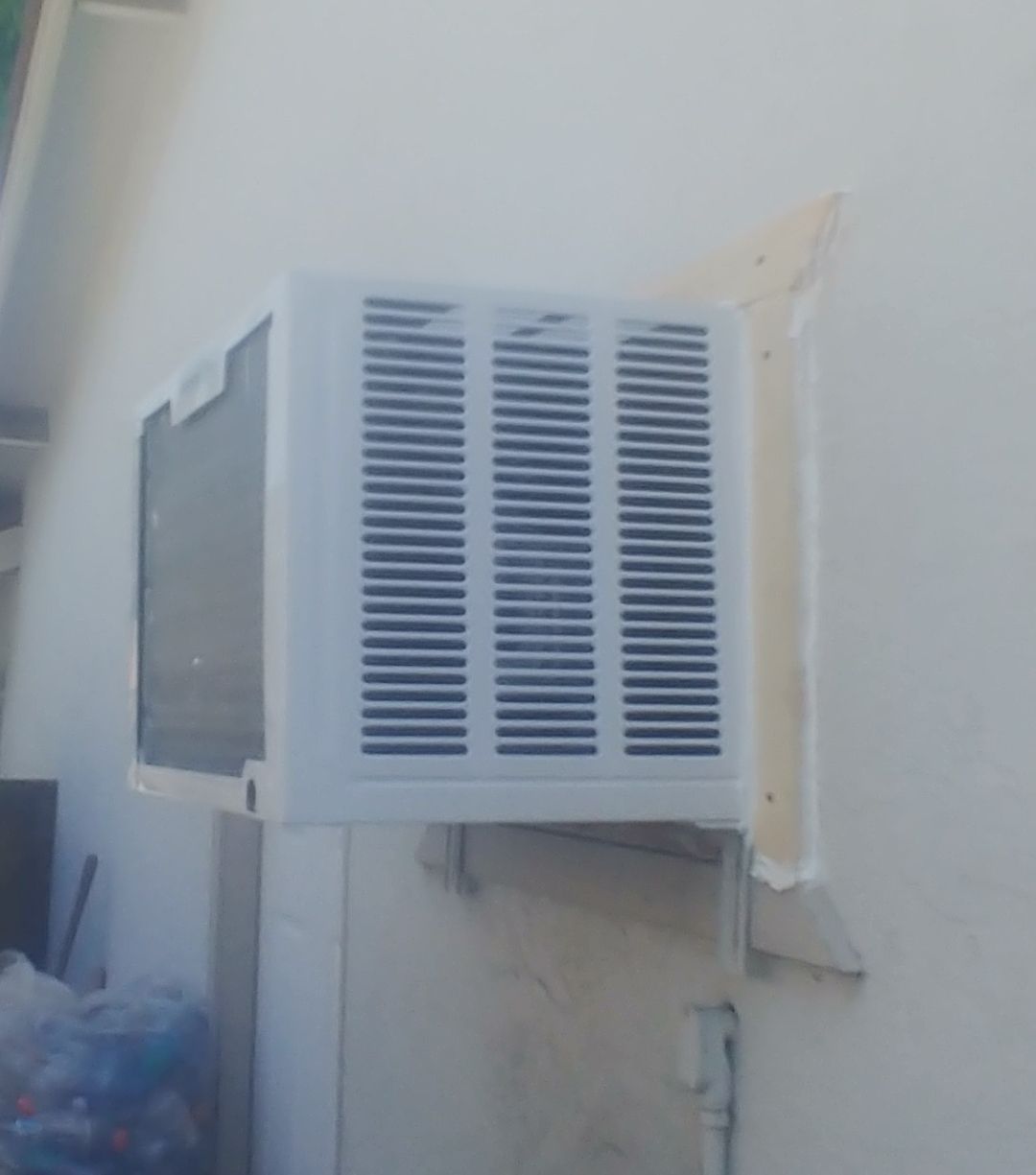 A white air conditioner is mounted on the side of a building.