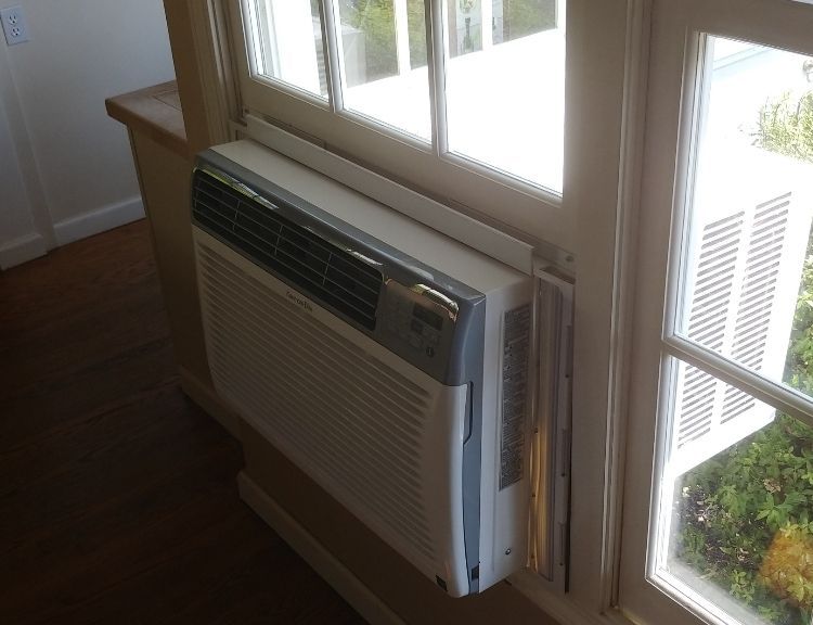 An air conditioner is mounted to the side of a window