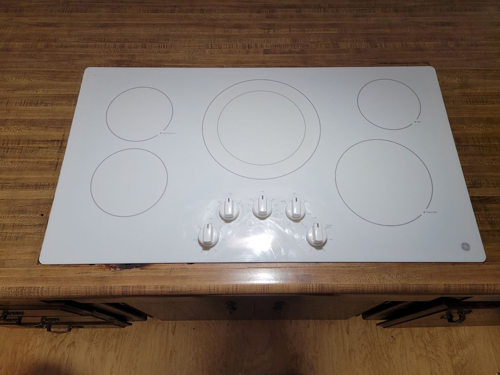 A white stove top oven is sitting on top of a wooden counter.