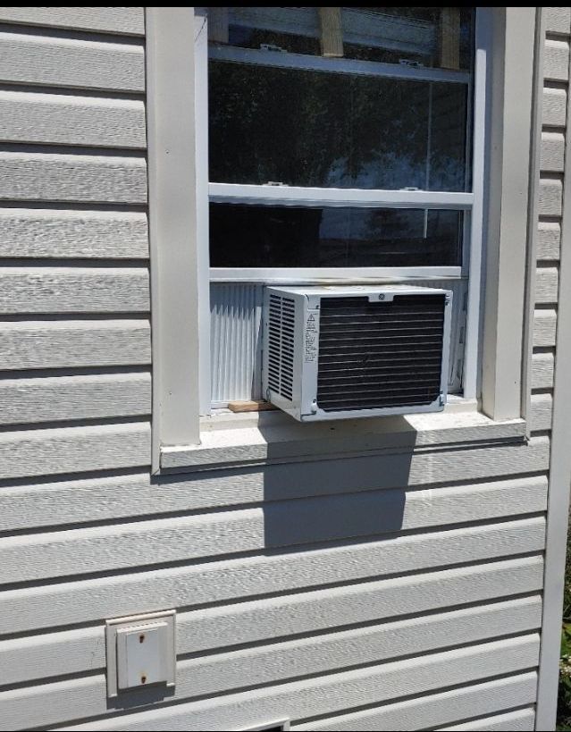 A window air conditioner mounted on the side of a house
