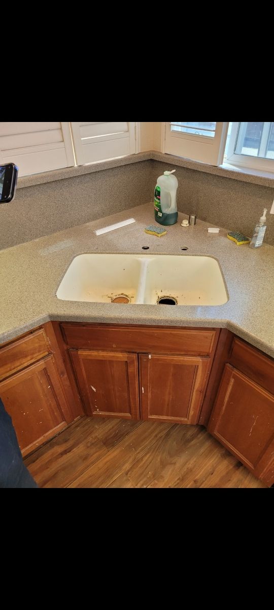 A kitchen sink with wooden cabinets and granite counter tops.